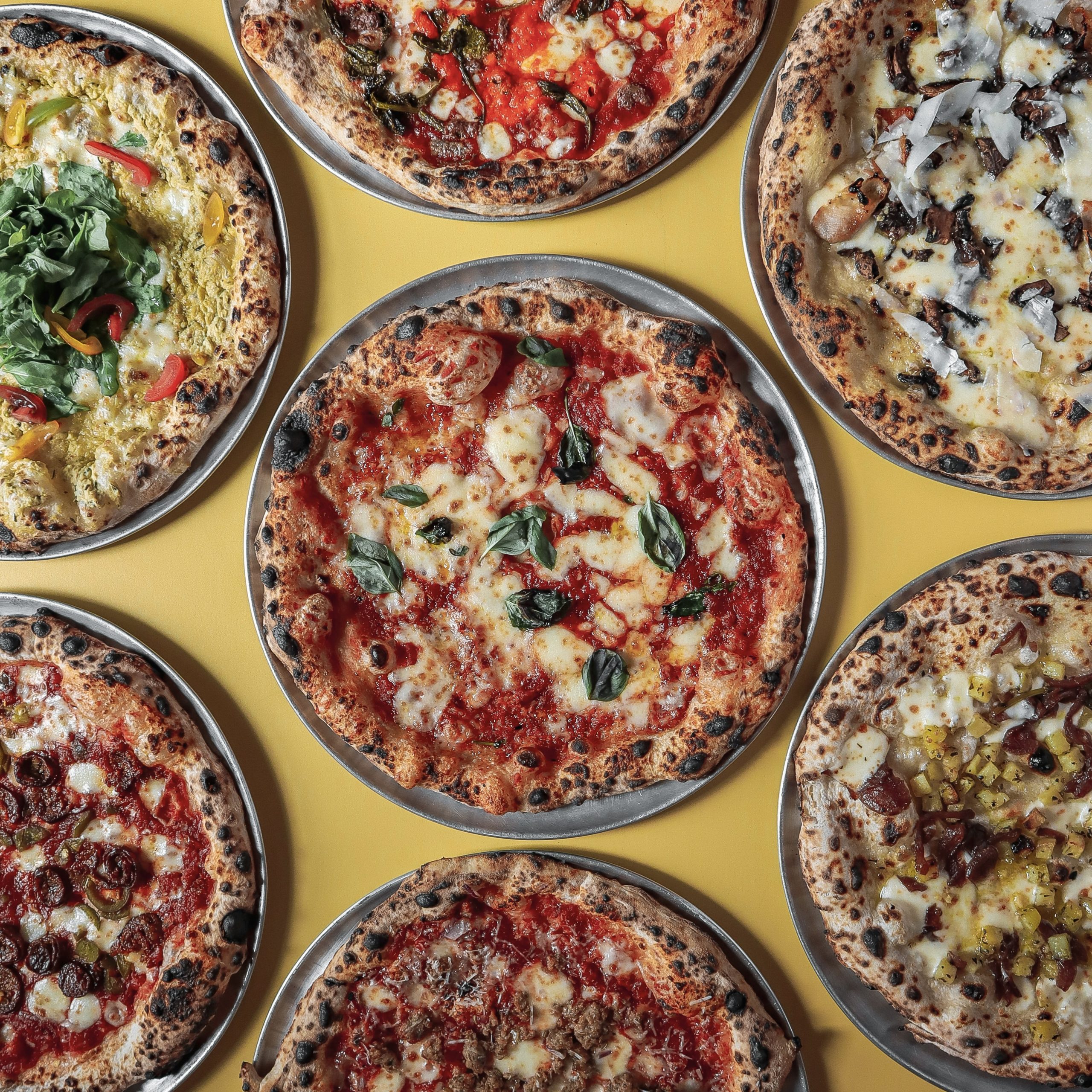 Vielfalt italienischer Pizzen auf gelbem Hintergrund